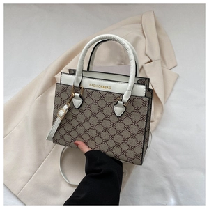 Detail view of cream and brown floral print handbag with golden metal hardware