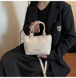 Détail du sac seau en paille avec poignées à nœuds et bandoulière en cuir assortie