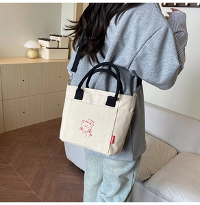 Detail of canvas bucket bag with red bear print, black handles and adjustable strap