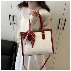 Detail of white embossed tote bag with red handles and decorative heart print scarf
