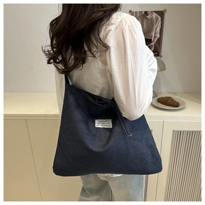 Detail view of deep blue denim tote bag with high-quality texture and woven label