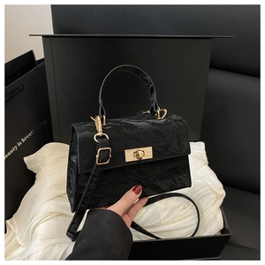 Detailed close-up of a black crinkled texture handbag with a gold metal rotary lock