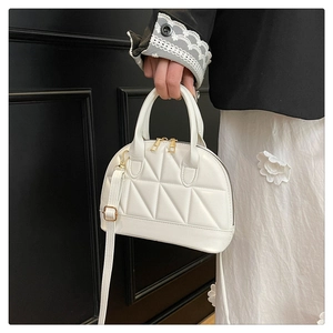 Close-up of a white quilted shell bag with golden hardware and adjustable strap