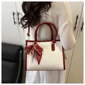 Detail of red and white faux crocodile tote bag with fashion scarf on a shoulder strap