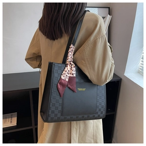 Dettaglio della borsa tote nera con goffratura a scacchi e accessorio foulard leopardato