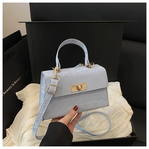 Detail of light blue wrinkled texture handbag with golden clasp in a gift box setup