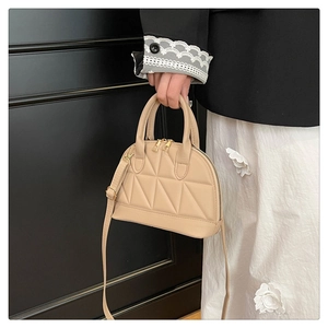 Detail of beige shell-shaped handbag featuring premium triangular quilted stitching