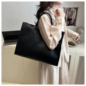 Détail d'un sac cabas noir en cuir effet crocodile avec de longues anses fines