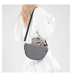 Détail du sac selle tissé gris avec poignée en métal argenté et bordure en cuir