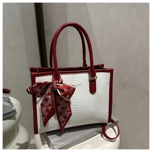 Detail of white crocodile-embossed tote bag with red leather trim and silk heart scarf