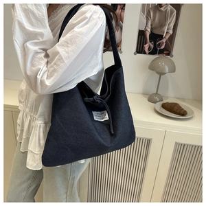 Detail of a large denim patchwork tote bag with white textile label in a cozy room