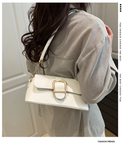 White underarm bag detail featuring a large gold horseshoe buckle and chain strap