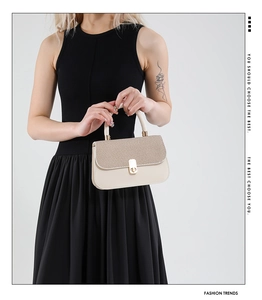 Detail of beige underarm bag with woven texture flap and golden metal lock buckle
