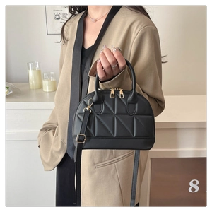 Detail of black quilted handbag with geometric patterns and dual metal zippers