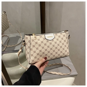 Dettaglio della borsa a tracolla beige con motivi floreali e cerniere in metallo oro