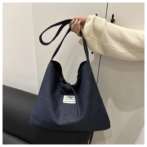 Detail of deep blue denim tote bag with drawstring closure and white fabric label