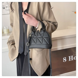 Detail of a black quilted shell bag with gold zippers and detachable leather shoulder strap
