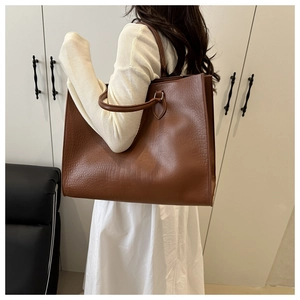 Détail d'un sac cabas marron effet crocodile porté à l'épaule par une femme