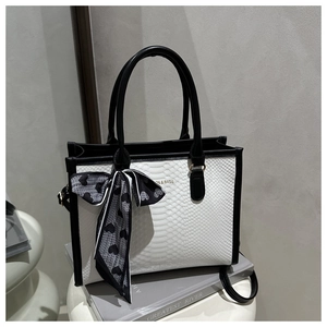 Detail of contrast tote bag featuring crocodile pattern texture and chic heart scarf