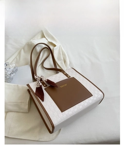 Dettaglio borsa tote bianca con trama intrecciata, tasca in pelle marrone e foulard leopardato