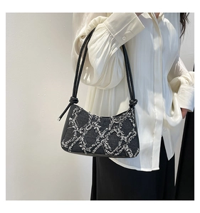 Detail of denim quilted crossbody bag with frayed edge grid pattern and knotted shoulder strap