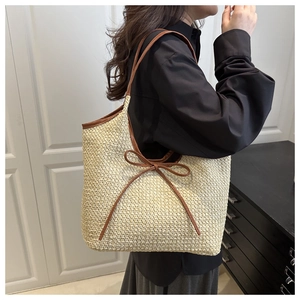 Détail d'un sac cabas tissé main avec anses en cuir marron et nœud de décoration élégant