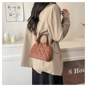 Brown quilted shell bag worn over the shoulder featuring metallic hardware and leather strap