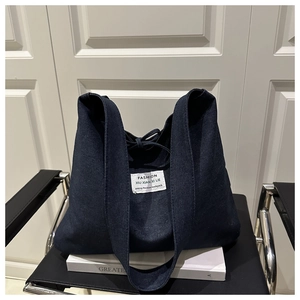 Close-up of deep blue denim patchwork tote bag with fashion label on white prop