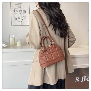 Detailed view of the brown quilted shell bag with golden zippers and leather strap