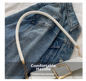 Detail view of white handbag with gold chain links, leather handle and square metal clasp