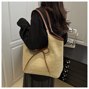 Vue détaillée d'un sac cabas en paille beige avec anses marron et nœud décoratif élégant