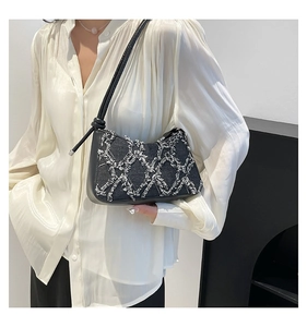 Quilted denim shoulder bag with white fringe details worn over a satin shirt