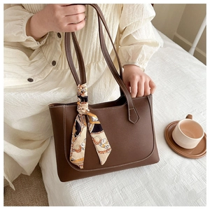 Détail du cabas en cuir marron avec surpiqûres contrastées blanches et foulard en soie