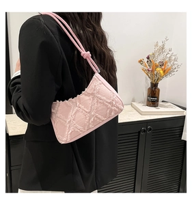 Pink quilted denim underarm bag with frayed texture shown on a female model