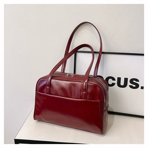 Detail of burgundy glossy faux leather tote bag with dual handles and secure zip closure