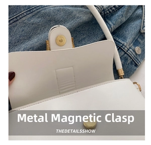 Close-up of golden magnetic clasp on white leather shoulder bag with neat stitching