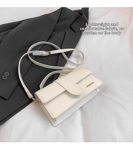 Top view of cream white shoulder bag on fabric background with professional blazer detail