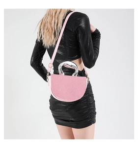 Détail du sac à main demi-lune rose avec poignée métallique en cœur et bandoulière fine