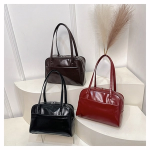Minimalist glossy faux leather shoulder bags in black and red displayed on white steps