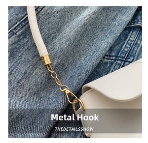 Macro detail of high-quality gold hardware hook and stitching on white leather bag