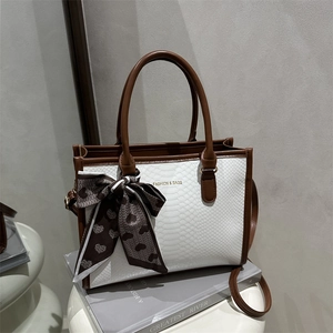White snakeskin tote bag with brown leather trim and decorative silk scarf handle