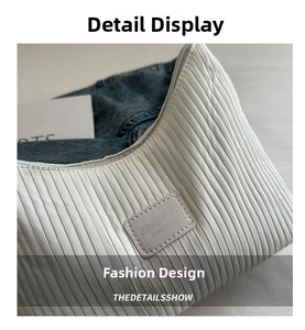 Detailed macro view of the white pleated fabric texture and stitched brand label on a tote bag