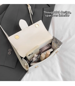 Detailed interior view of white crossbody bag with rabbit ear design and gold magnetic snaps