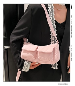 Dettaglio borsa a tracolla in nylon trapuntato rosa con doppie tasche indossata da modella