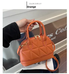 Detail of orange quilted handbag with geometric stitching and gold metal hardware
