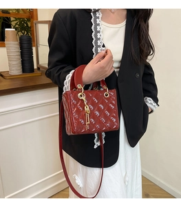 Detail view of red patent leather quilted handbag with gold handle and key charm