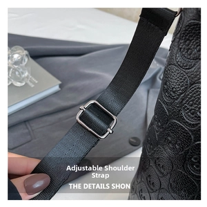 Close-up of adjustable strap with silver metal buckle on embossed skull pattern handbag