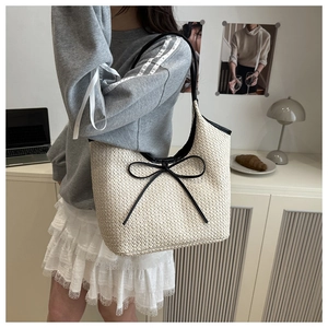 Détail d'un sac cabas tissé beige avec nœud noir et bandoulières contrastantes