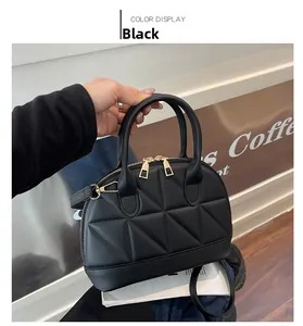 Detailed view of black quilted crossbody bag with gold hardware and geometric stitching