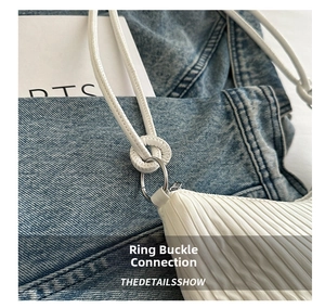 Detail of silver metal buckle connecting the white pleated shoulder bag strap